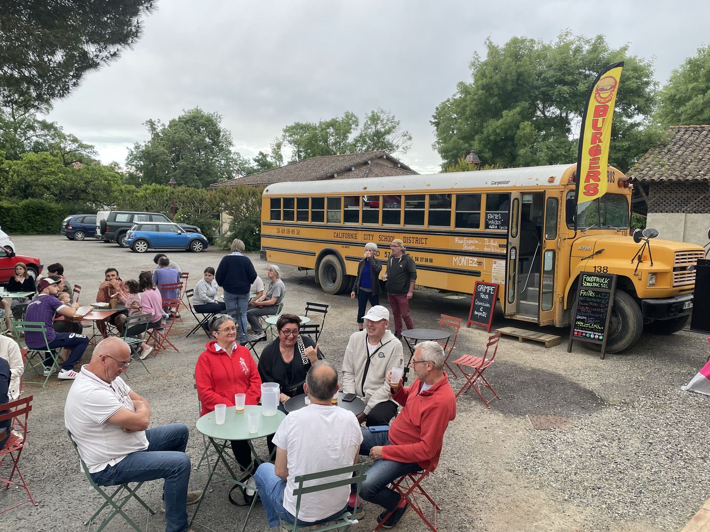 Habitants attablés en terrasse devant le bus jaune de la buvette, un jour de marché