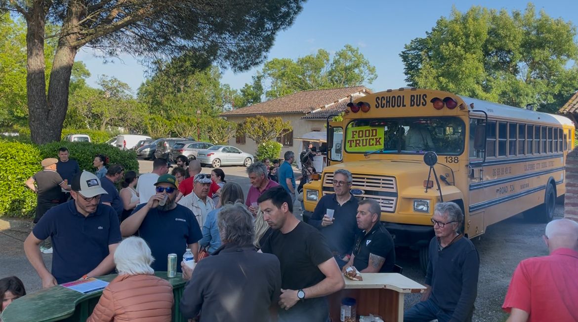 Buvette du marché devant un bus scolaire jaune transformé en food truck, entourée de convives