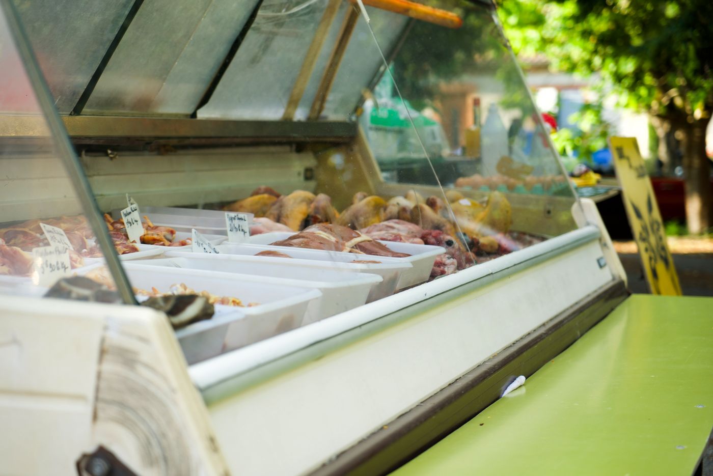 Vitrine réfrigérée garnie de viandes et de charcuteries sur un étal du marché