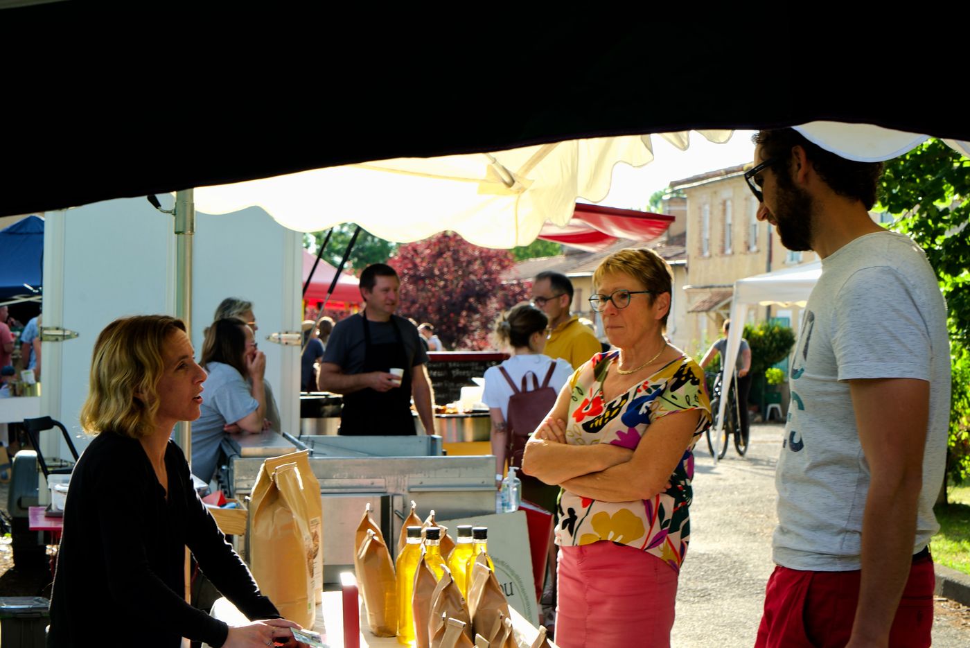 Producteurs et visiteurs discutent devant un étal du marché