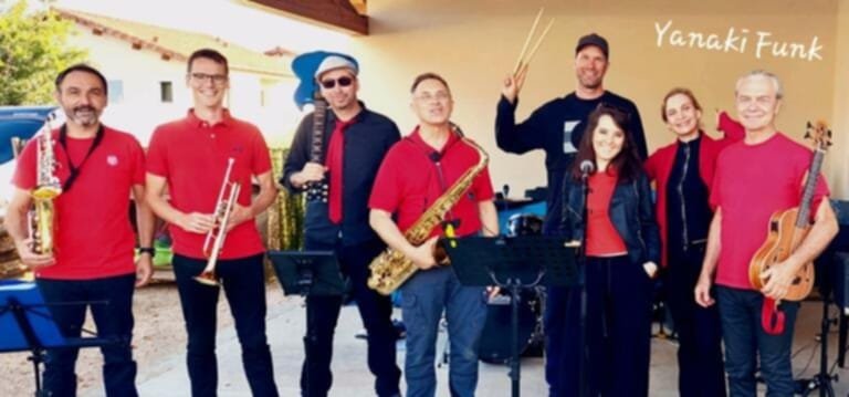 Un orchestre de cuivres en chemises rouges pose avec saxophones, trompettes et batterie